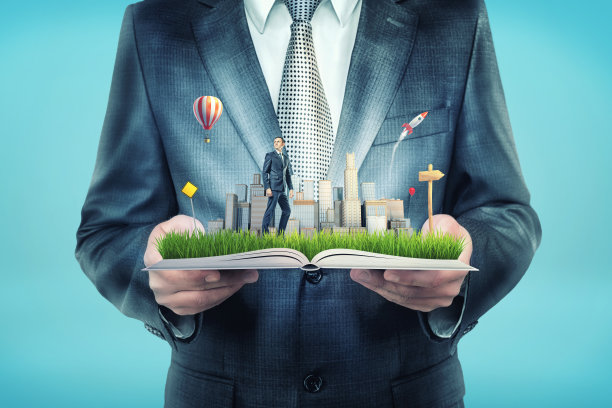 一个巨大的商人拿着一本打开的书，上面也有一个小商人站在摩天大楼附近的空地上。图片下载
