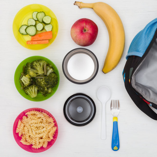 俯视图的午餐盒，热水瓶和健康食品的学校选择。一天的零食。热午餐，外卖。黄瓜，胡萝卜，花椰菜，苹果，香蕉和意大利面。图片下载