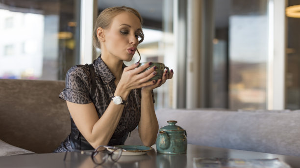 一位戴着眼镜的性感商人正在一家咖啡馆里喝热茶。图片下载