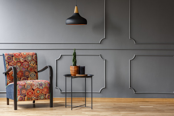 黑色的顶灯在带有植物和扶手椅的工业边桌上方，客厅内部有一个橱柜。真实的照片。图片下载