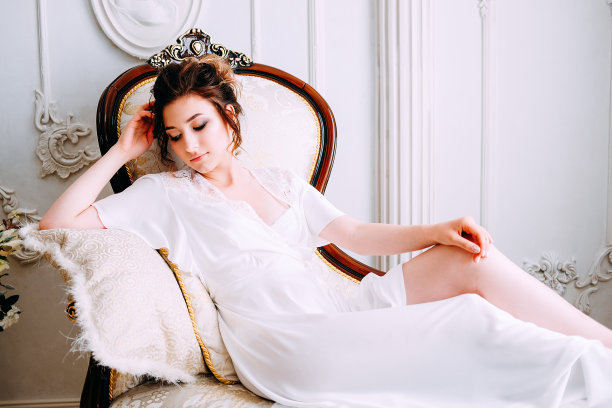 性感的黑发在丝绸白色长袍等在长椅上图片下载