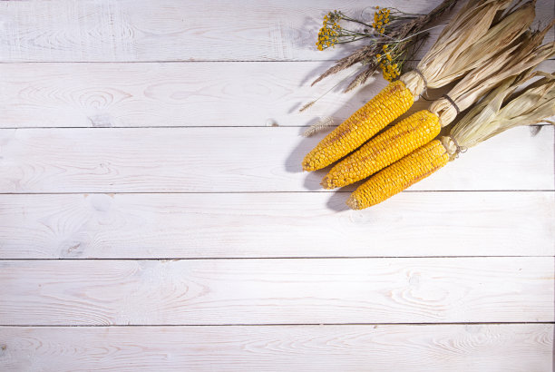 木质背景上的烤玉米棒。前视图。图片下载