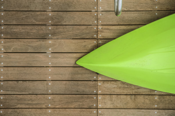 船首翻倒的绿色皮艇躺在一个天然木码头与铬扶手的一部分在一边图片下载