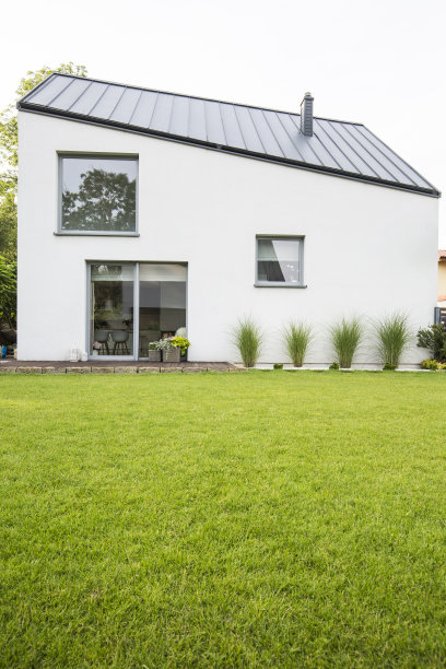 在一个有木制阳台的豪华房子的后院的绿色草坪在夏天。真实的照片图片下载