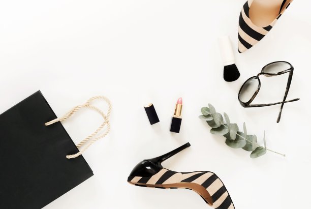 平躺，俯视图的女性时尚配件。米色手袋，太阳镜，高跟鞋和化妆品在白色背景。本空间图片下载