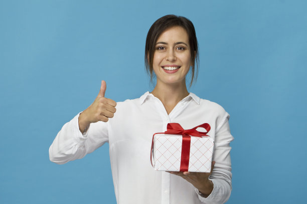 年轻漂亮的女人微笑着有礼物。蓝色背景图片下载