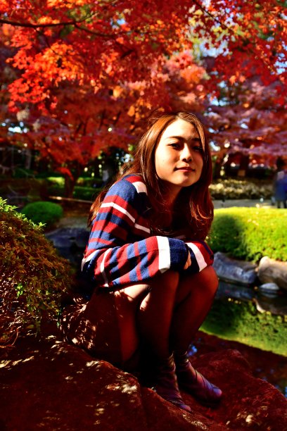 年轻的日本女人在明亮的秋叶下放松，东京图片下载