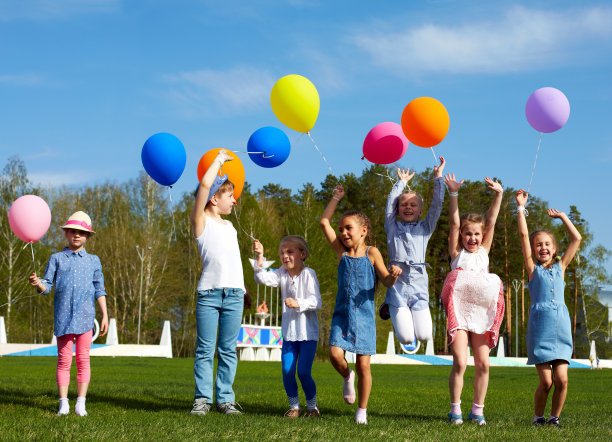 一大群快乐的孩子在户外拿着气球图片下载