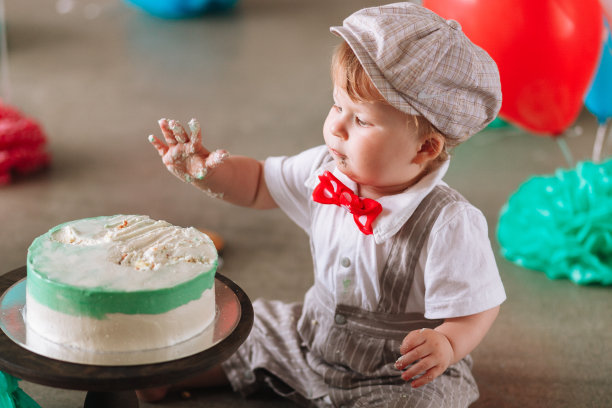 小男孩在摸他的第一个生日蛋糕。在装饰过的工作室里做蛋糕图片下载
