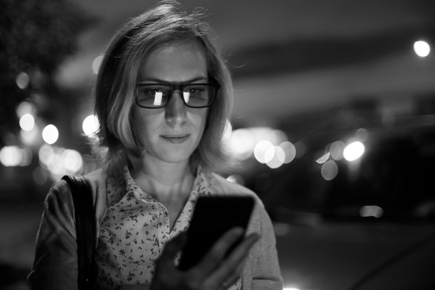 一个年轻女子在户外使用智能手机的特写图片下载