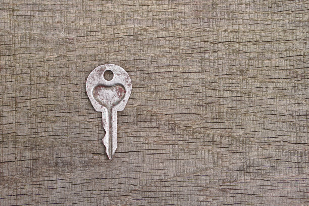 情人节或婚礼的浪漫背景。一把旧钥匙，在一块旧木板上刻着一颗心。设计素材照片图片下载