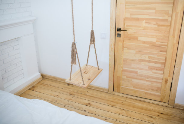 木秋千与乡村绳索在房间阁楼内部。白色的砖墙公寓。图片下载