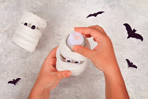从一个罐子工艺品。妈妈从一个罐子和绷带和蝙蝠在一个轻桌上。万圣节的概念。DIY。图片下载
