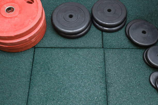 红色和黑色的沉重杠铃板放在绿色的橡胶地板上。模拟运动训练提供。副本的空间。文本的空位置。前视图。图片下载