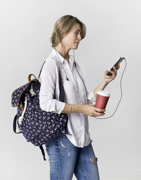 快乐年轻的学生女孩用智能手机背包图片下载