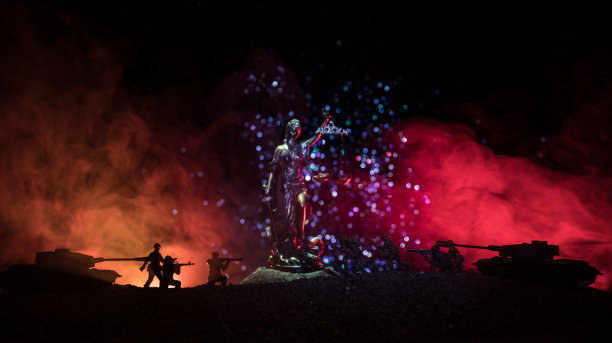 战争-没有正义的概念。军事剪影的战斗场景和在黑暗色调的雾背景上的正义雕像。图片下载