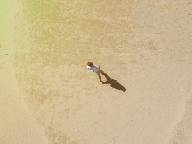 空中俯瞰的年轻人独自走在沙滩上，抽象概念背景f图片下载