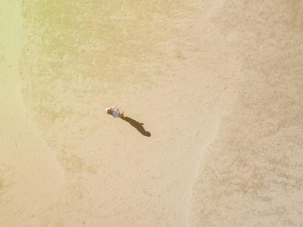 空中俯瞰的年轻人独自走在沙滩上，抽象概念背景f图片下载