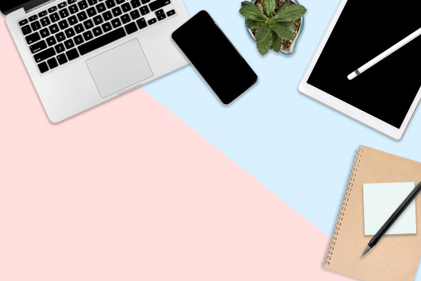 平放办公桌子与笔记本电脑，数字平板电脑，手机和配件的照片。对现代的两种色调(蓝色和粉色)背景。桌面办公室模型概念。图片下载