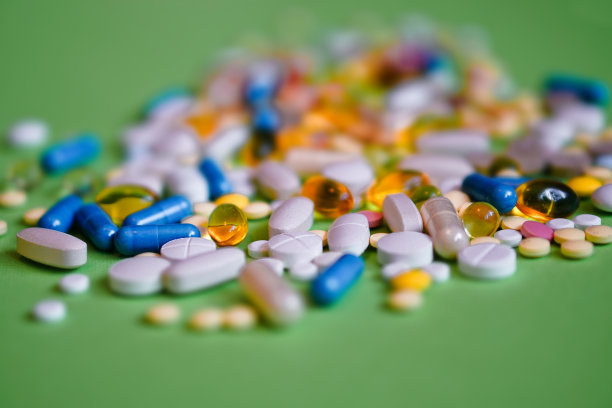绿色背景上是各种药品，药片，胶囊和瓶子。毒品和各种麻醉药品。为文本复制空间。设计素材照片图片下载