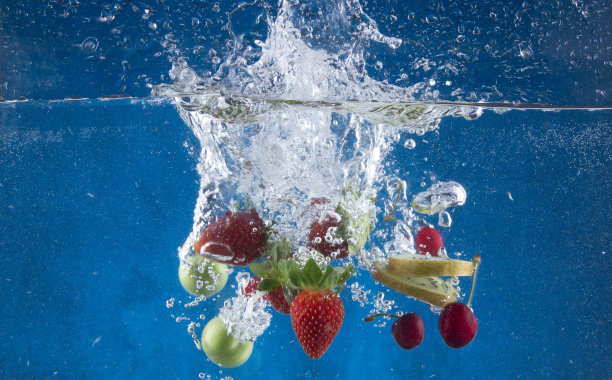 水果溅到水上。新鲜健康的水果被戏剧性地浸入干净的水中时拍摄的照片。图片下载