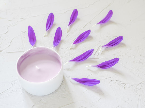 紫色的化妆品霜和紫色的花瓣在白色的背景。创意美时尚化妆品照片。平躺图片下载