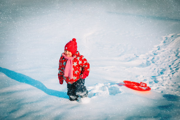 快乐的小女孩享受雪上骑行，冬天小朋友的活动图片下载