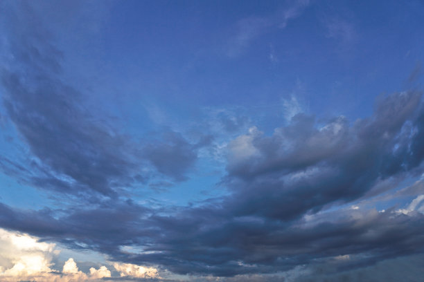 美丽的白色和灰色的云映衬着蓝色的天空。夏秋之日，从飞机上望向大气。设计素材照片图片下载