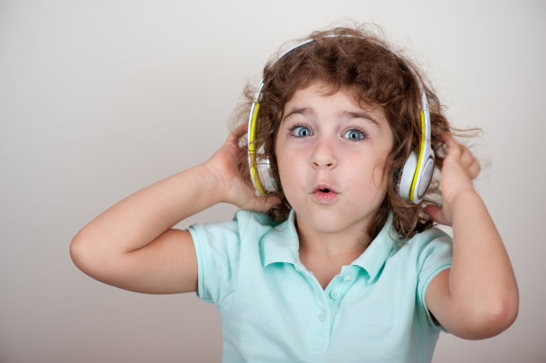 孩子戴着耳机，享受着声音，双手拿着耳机图片下载