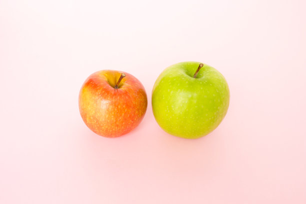 粉红背景上的红苹果和绿苹果图片下载