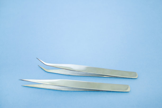 睫毛延长程序的工具。蓝色背景上的两把镊子。copyspace模型-美丽和时尚的概念图片下载