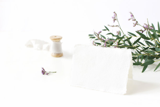 明亮的女性文具模型场景手工纸的地方卡，线轴丝带，桉树叶和紫罗兰补习班花在白色的桌子背景。婚礼摄影风格图片下载