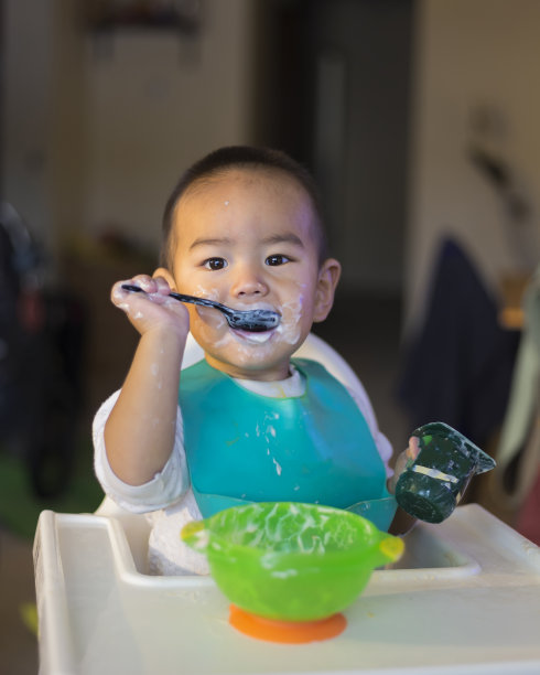 一个可爱的婴儿正在高脚椅上吃酸奶图片下载