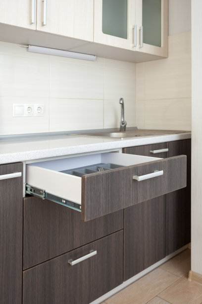 休闲、生活方式、居家生活理念。侧面的垂直照片打开木制抽屉的刀，叉，勺子下的白色烹饪桌子对白色墙砖图片下载