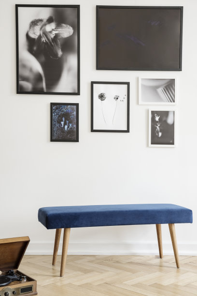 在客厅内部，深蓝色的长凳靠着白色的墙壁，墙上挂着海报。真实的照片图片下载
