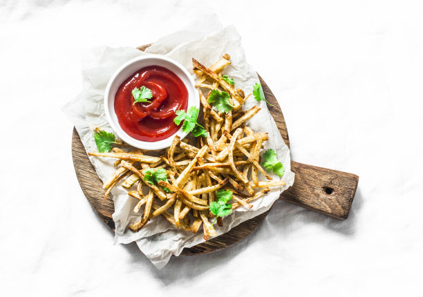 烤欧防风薯条和自制蕃茄酱在切板上-健康的素食零食在光的背景，俯视图图片下载
