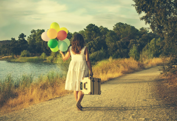 在乡下，一个女人拿着彩色的气球和手提箱图片下载