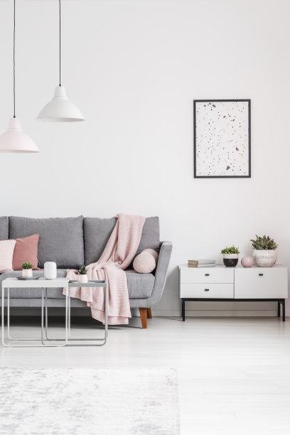 海报上方的橱柜旁边的灰色沙发在白色的客厅内部与灯。真实的照片图片下载