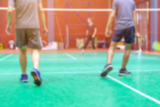 背景模糊的羽毛球运动员在绿色的球场。图片下载