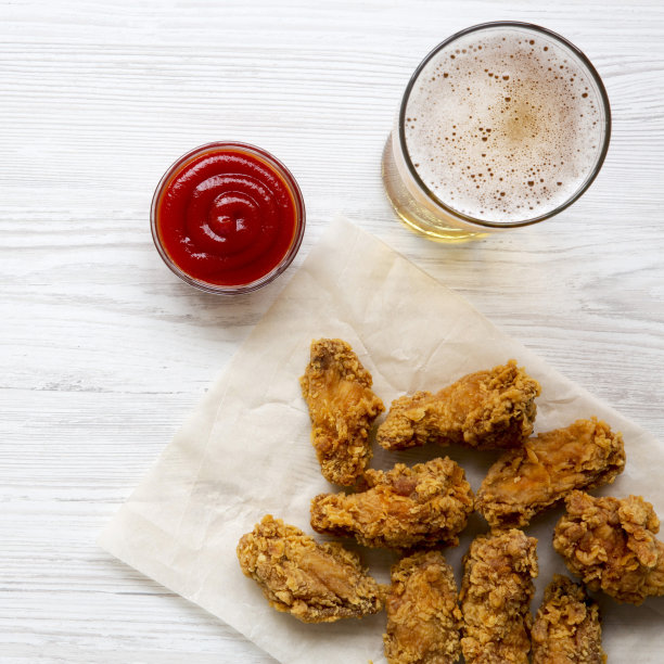 炸鸡翅配番茄酱，白木桌上放着冰啤酒，俯视图。从上面的开销。特写镜头。图片下载