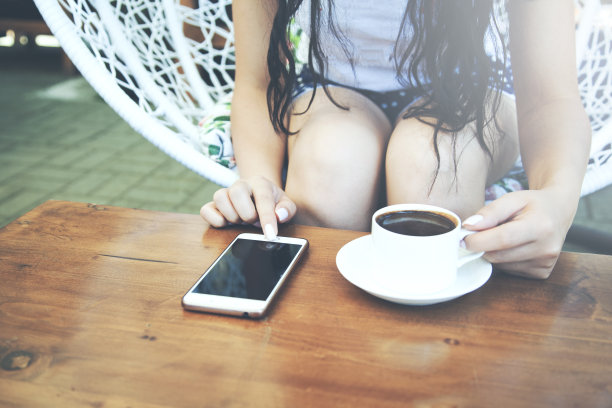 一个女人坐在咖啡馆里拿着手机端着咖啡图片下载