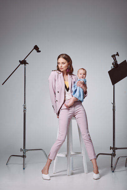 时尚的年轻妈妈抱着可爱的婴儿女儿坐在录音棚的凳子上图片下载