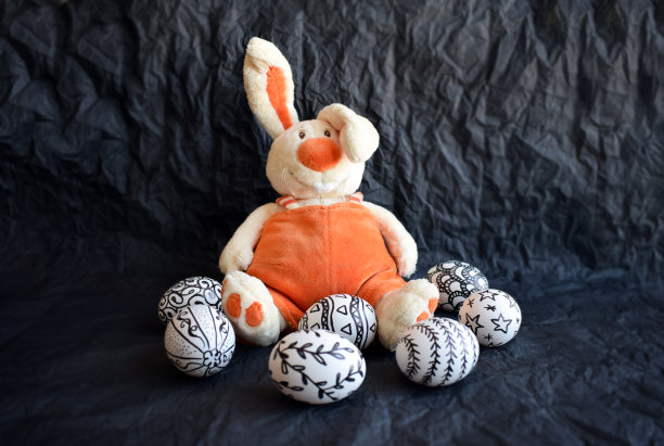 复活节彩蛋手绘不同的涂鸦图案和可爱的橙色玩具兔子在黑色的背景。帕沙鸡蛋与涂鸦不同寻常décor和复制空间。复活节快乐装饰现代风格图片下载