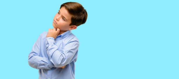 英俊的蹒跚学步的孩子，绿色的眼睛，思考和仰望表达怀疑和惊奇图片下载