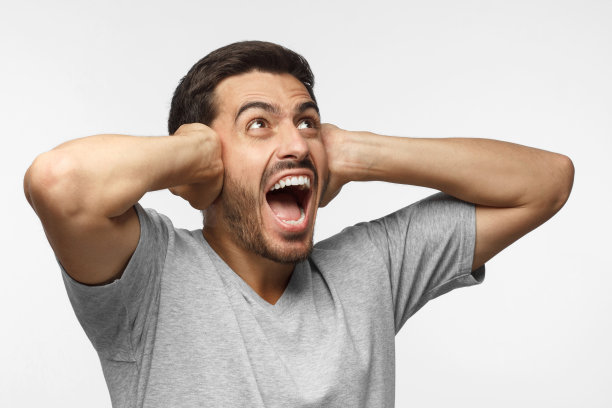 年轻人对着吵闹的邻居大喊大叫，受到噪音的压力，双手紧闭耳朵图片下载