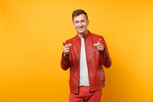 肖像时尚微笑帅气的年轻人25-30岁身穿红色皮夹克，t恤孤立地站在明亮的趋势黄色背景上。人真诚情感生活理念。广告区域。图片下载