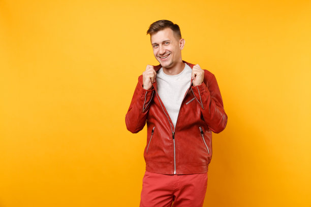 肖像时尚自信帅气的年轻人25-30岁身穿红色皮夹克，t恤孤立地站在明亮的趋势黄色背景上。人真诚情感生活理念。广告区域。图片下载