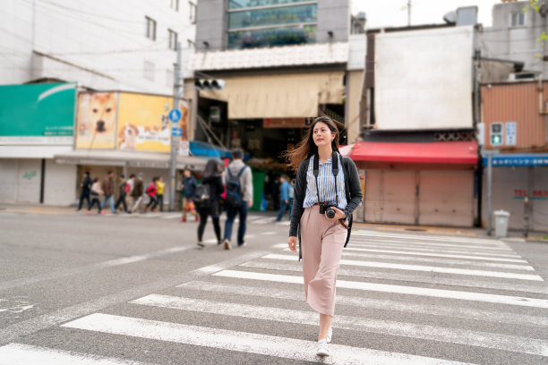 漂亮的亚洲女人过马路。图片下载