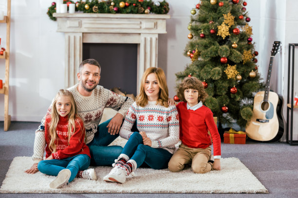 快乐的父母和孩子们一起坐在地板上看着镜头图片下载