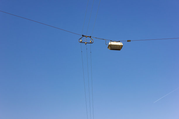 湛蓝的夏日阳光普照前，电线上挂着电灯图片下载